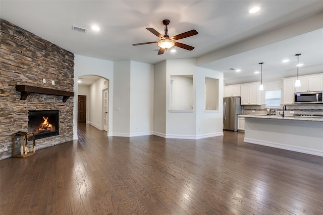 unfurnished living room featuring dark hardwood / wood-style flooring, ceiling fan, a fireplace, and sink