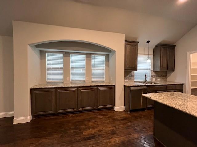 kitchen with vaulted ceiling, dark hardwood / wood-style floors, pendant lighting, dishwasher, and sink