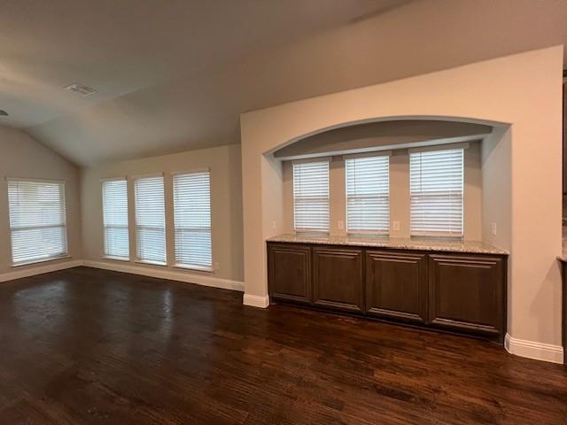 empty room featuring dark wood-type flooring and vaulted ceiling