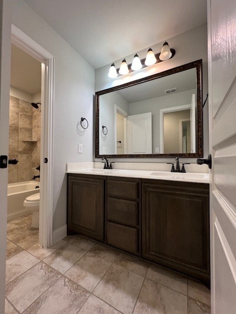 full bathroom featuring vanity, tiled shower / bath combo, and toilet