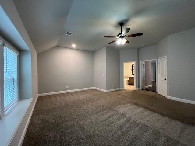 spare room with dark carpet, ceiling fan, and lofted ceiling