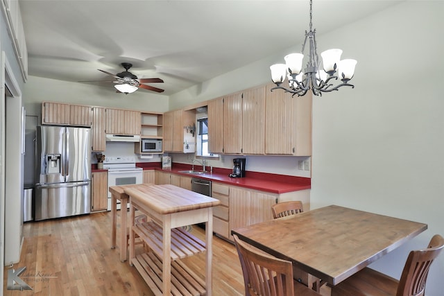 kitchen featuring sink, stainless steel appliances, pendant lighting, light hardwood / wood-style floors, and ceiling fan with notable chandelier