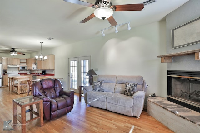 living room featuring ceiling fan with notable chandelier and light hardwood / wood-style flooring