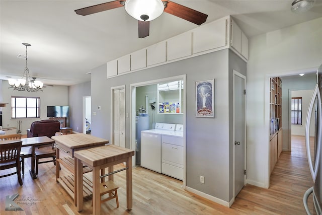 dining area with ceiling fan with notable chandelier, light hardwood / wood-style flooring, and washing machine and clothes dryer