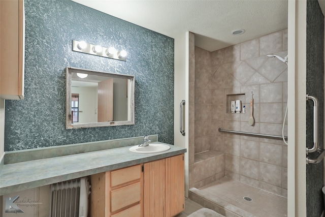 bathroom with tiled shower, a textured ceiling, and vanity