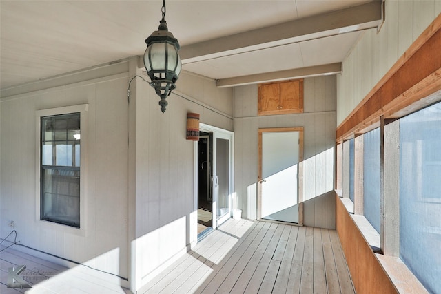 unfurnished sunroom featuring beam ceiling