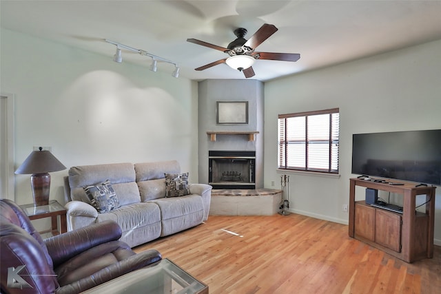 living room with light wood-type flooring, rail lighting, and ceiling fan