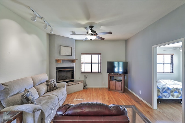 living room with ceiling fan, plenty of natural light, rail lighting, and light wood-type flooring