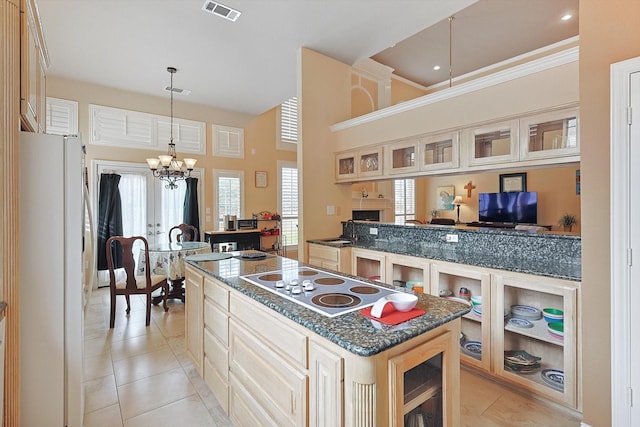 kitchen with light tile patterned floors, white refrigerator, electric cooktop, a chandelier, and a center island