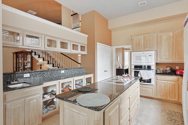 kitchen with light tile patterned flooring, dark stone countertops, white appliances, and sink