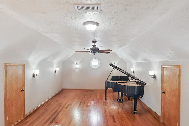 misc room with lofted ceiling, ceiling fan, a textured ceiling, and hardwood / wood-style flooring