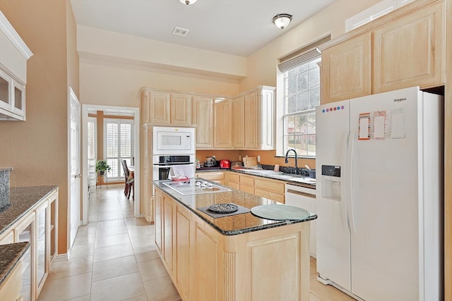 kitchen featuring a healthy amount of sunlight, light tile patterned floors, white appliances, and dark stone counters