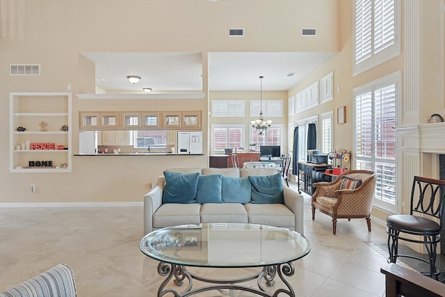 living room featuring a high ceiling, light tile patterned floors, built in features, and a notable chandelier