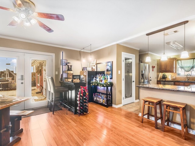 interior space featuring stone counters, french doors, crown molding, light hardwood / wood-style floors, and appliances with stainless steel finishes