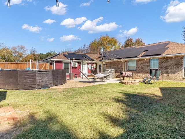 rear view of property with solar panels, a patio area, and a yard