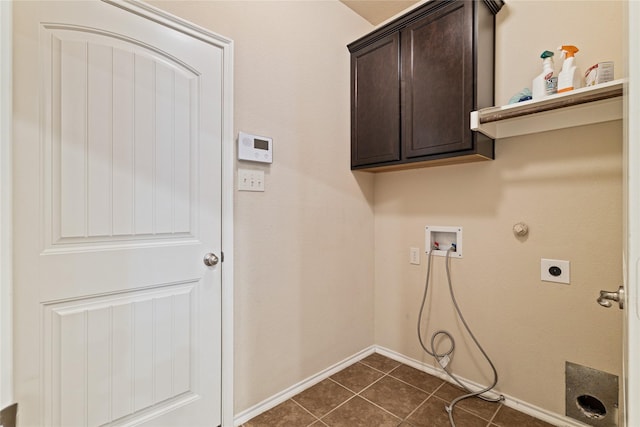 washroom with electric dryer hookup, cabinets, gas dryer hookup, dark tile patterned flooring, and washer hookup