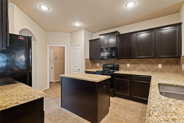 kitchen with backsplash, light stone countertops, a kitchen island, and black appliances