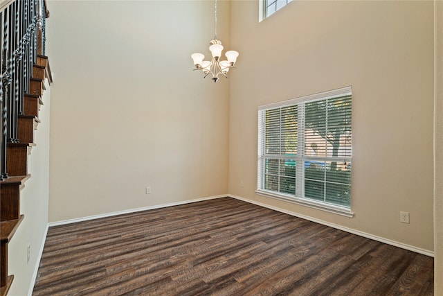 spare room with a chandelier, a high ceiling, and dark hardwood / wood-style flooring