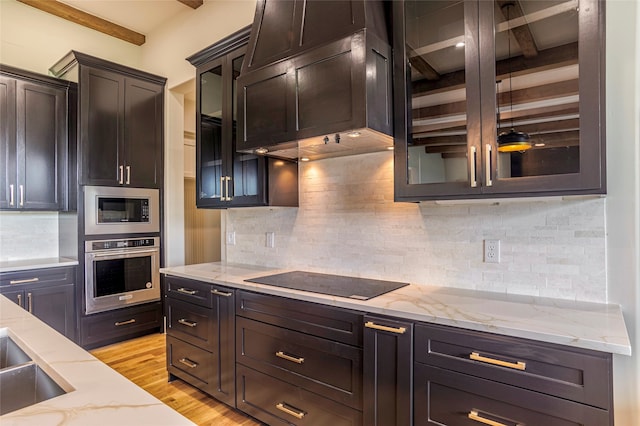 kitchen featuring light stone counters, backsplash, appliances with stainless steel finishes, and light hardwood / wood-style flooring