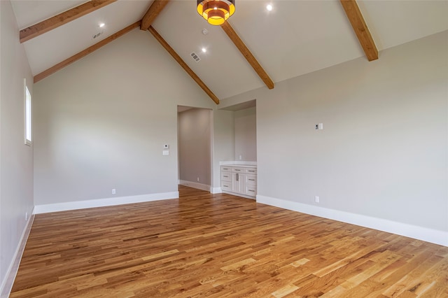 empty room with beamed ceiling, high vaulted ceiling, and light wood-type flooring