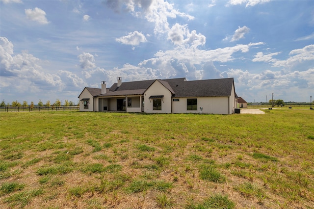 back of house with a yard and a rural view