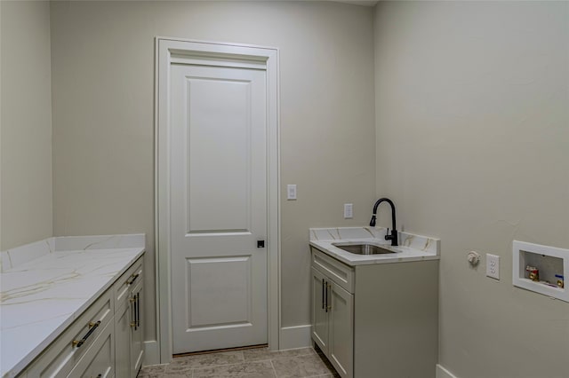 clothes washing area with hookup for a washing machine, sink, and cabinets