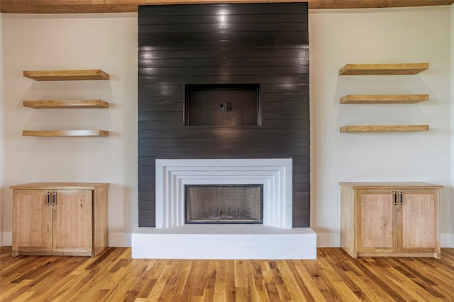 unfurnished living room featuring light wood-type flooring and a large fireplace