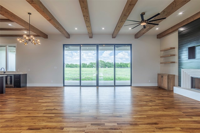 unfurnished living room with hardwood / wood-style floors, ceiling fan with notable chandelier, beam ceiling, and a fireplace