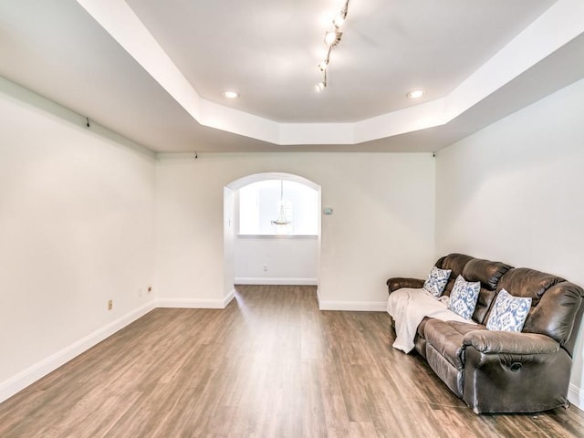 sitting room with track lighting, a raised ceiling, and hardwood / wood-style floors