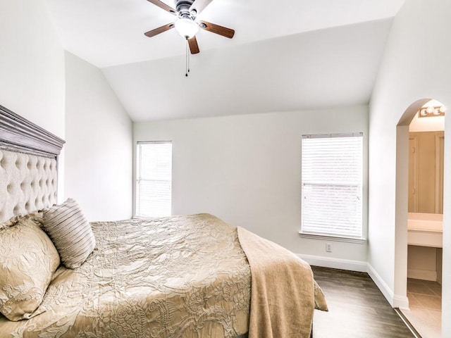 bedroom featuring multiple windows, ceiling fan, vaulted ceiling, and ensuite bath