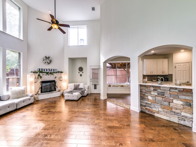 living room with a high ceiling, a healthy amount of sunlight, dark hardwood / wood-style floors, and a fireplace