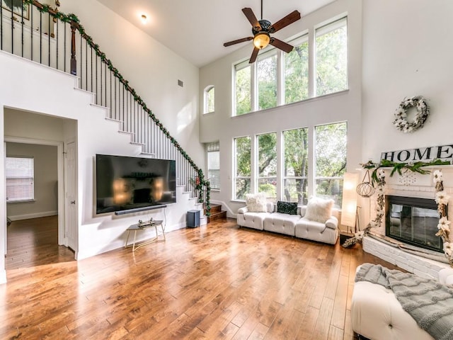 living room with a healthy amount of sunlight, wood-type flooring, a fireplace, and a high ceiling