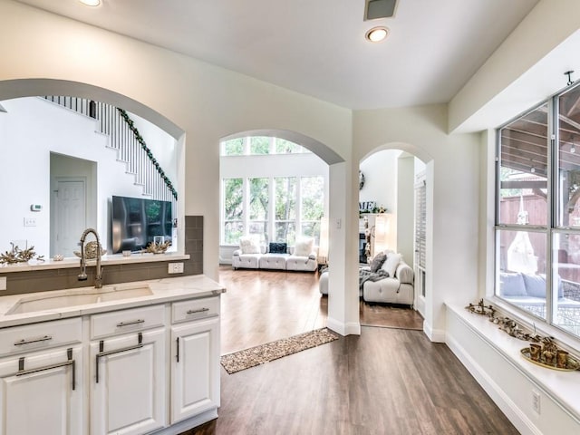 kitchen featuring white cabinetry, sink, light stone counters, and dark hardwood / wood-style flooring