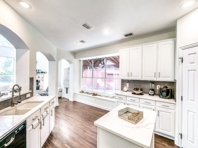 kitchen featuring sink, white cabinetry, light stone counters, black dishwasher, and a kitchen island