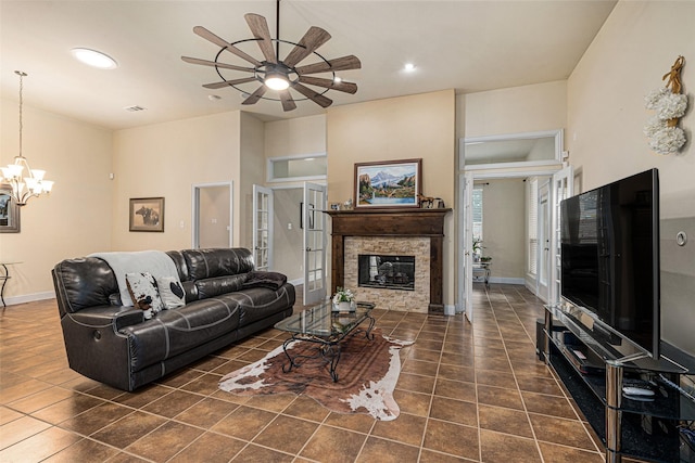 tiled living room featuring ceiling fan with notable chandelier and a fireplace