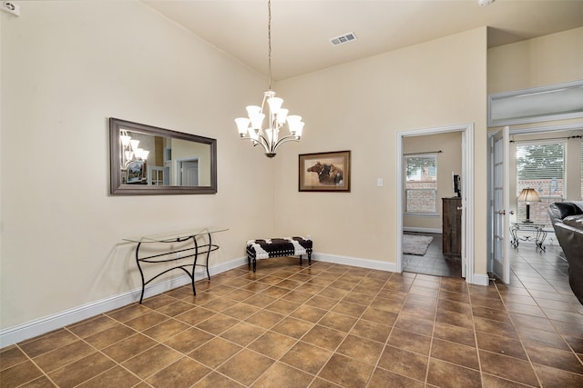 living area featuring a notable chandelier, dark tile patterned floors, and lofted ceiling