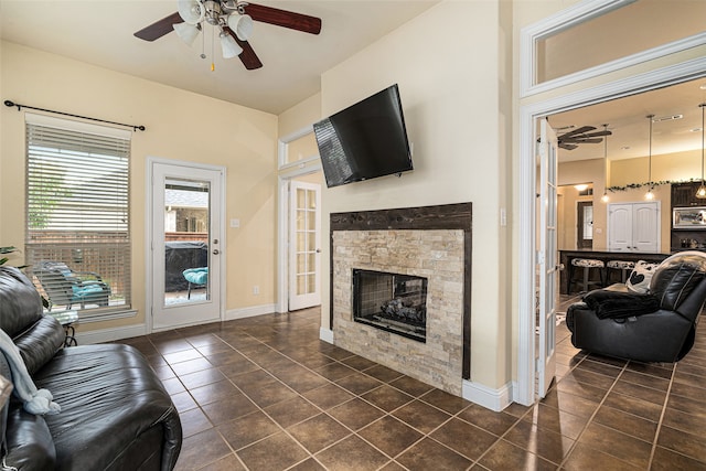 living room featuring a fireplace, ceiling fan, and dark tile patterned flooring