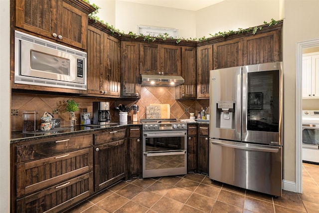 kitchen with washer / clothes dryer, dark stone countertops, stainless steel appliances, decorative backsplash, and dark brown cabinetry