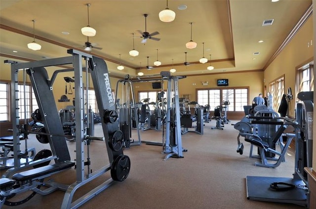 gym with ceiling fan, a tray ceiling, and crown molding