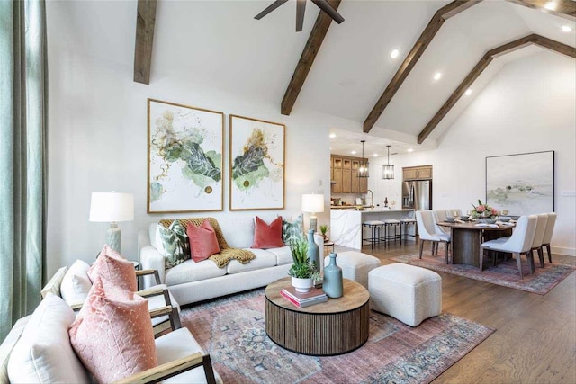 living room featuring sink, high vaulted ceiling, dark hardwood / wood-style floors, ceiling fan, and beam ceiling