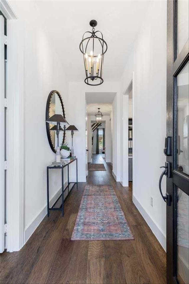 entryway with dark wood-type flooring and a chandelier