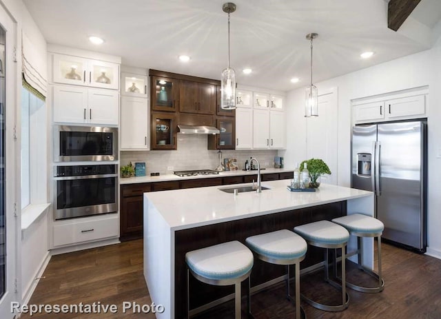 kitchen with dark hardwood / wood-style flooring, sink, stainless steel appliances, and a center island with sink