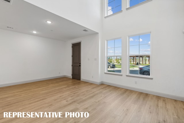 interior space featuring a towering ceiling, plenty of natural light, and light wood-type flooring