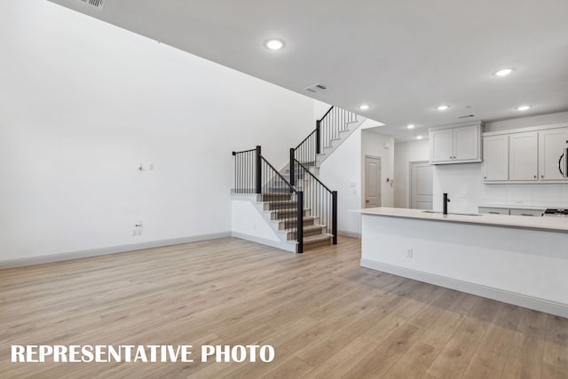 unfurnished living room with sink and light hardwood / wood-style floors