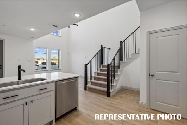 kitchen with white cabinetry, dishwasher, sink, and light wood-type flooring