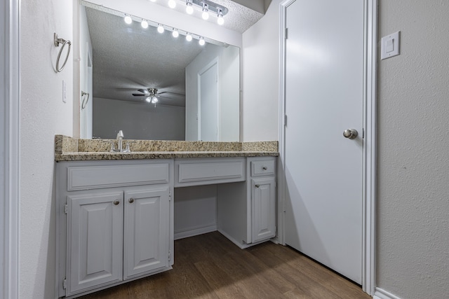 bathroom featuring vanity, ceiling fan, wood-type flooring, and a textured ceiling