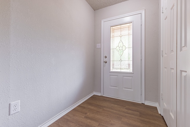 doorway to outside with dark wood-type flooring and a textured ceiling