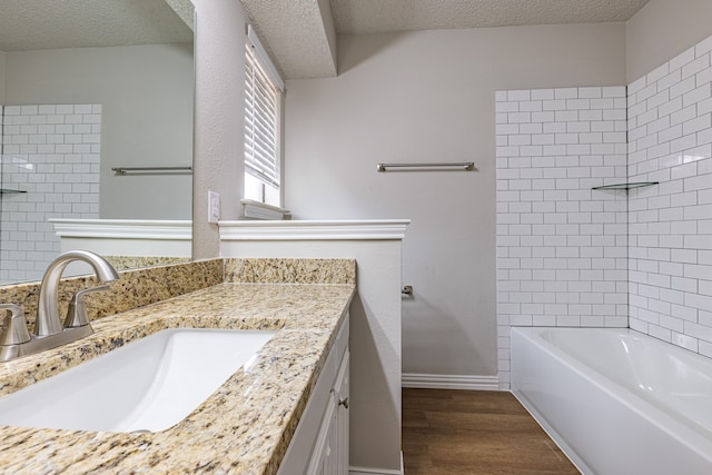 bathroom featuring hardwood / wood-style floors, vanity, a textured ceiling, and tiled shower / bath