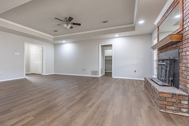 unfurnished living room with a tray ceiling, crown molding, ceiling fan, and wood-type flooring