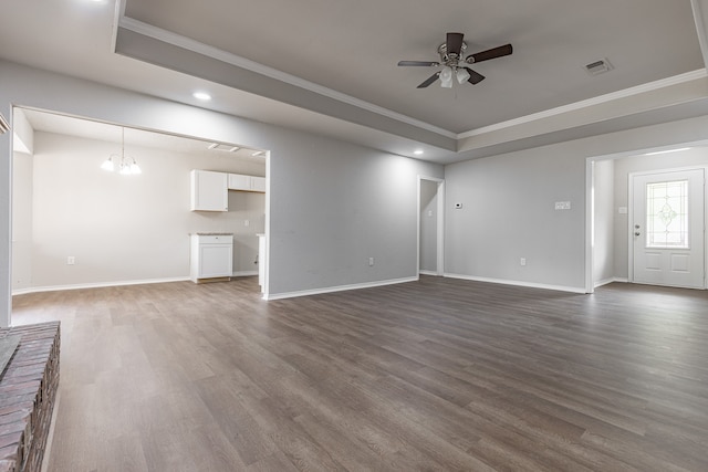 unfurnished living room with ornamental molding, ceiling fan with notable chandelier, a raised ceiling, and dark wood-type flooring